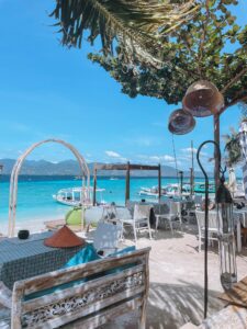 Relaxing beachfront scene with chairs, tables, and clear turquoise waters in West Nusa Tenggara.